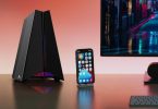 Routeur gaming WiFi 7 TP-Link Archer GE550 avec éclairage RGB posé sur un bureau à côté d’un smartphone