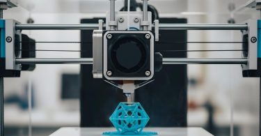 Imprimante 3D de précision en plein travail sur une structure géométrique bleue, illustrant la nécessité d'outils de finition et de mesure pour un résultat professionnel.