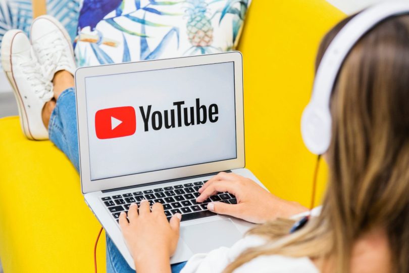 Jeune élève avec un casque audio utilisant un ordinateur portable affichant le logo YouTube, illustrant la consommation massive de vidéos et les risques d'addiction aux écrans en milieu scolaire.