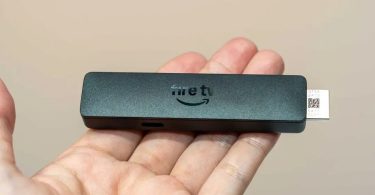Amazon Fire TV Stick HD 2026 tenu dans une main, montrant son design affiné et son connecteur HDMI