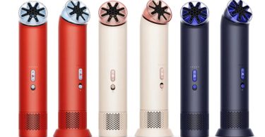 Une femme élégante avec des lunettes de soleil aviateur regarde vers le haut tout en tenant le ventilateur portable Dyson HushJet Mini Cool de couleur Stone Blush, mettant en valeur son design compact et la technologie miniaturisée Air Multiplier.