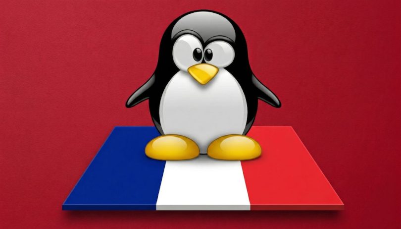 Mascotte Tux de Linux debout sur un socle aux couleurs du drapeau français, sur fond rouge uni. Symbole de la migration vers l'open source.