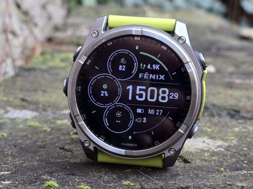 Gros plan sur une montre Garmin Fenix 7 avec bracelet jaune fluo posée sur de la mousse, affichant le cadran d'activité principal. L'image illustre le type d'appareil haut de gamme bénéficiant du nouveau mode de récupération sans perte de données.