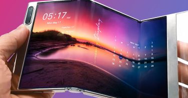 Gros plan sur un prototype de smartphone Huawei tri-pliable affichant un paysage au coucher du soleil sur un grand écran OLED flexible, tenu en main pour illustrer son double mécanisme de charnière en Z.