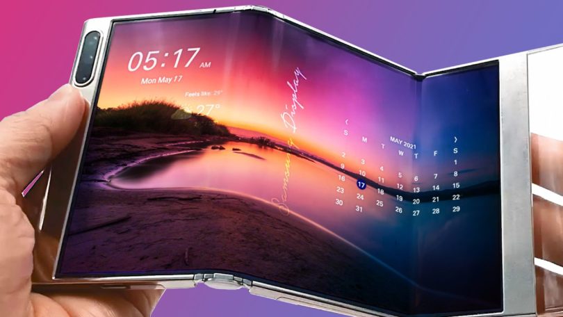 Gros plan sur un prototype de smartphone Huawei tri-pliable affichant un paysage au coucher du soleil sur un grand écran OLED flexible, tenu en main pour illustrer son double mécanisme de charnière en Z.