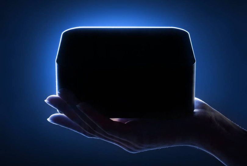 Silhouette d'un mini PC Lenovo compact et premium, tenu dans la paume d'une main avec un rétroéclairage bleu vif soulignant ses contours épurés sur un fond sombre.