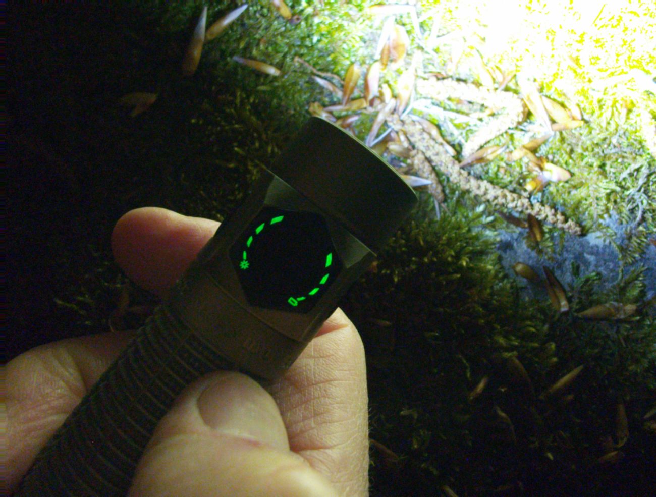 Olight Baton Ultra - microperforations laser side button allumées en vert dans l'obscurité totale