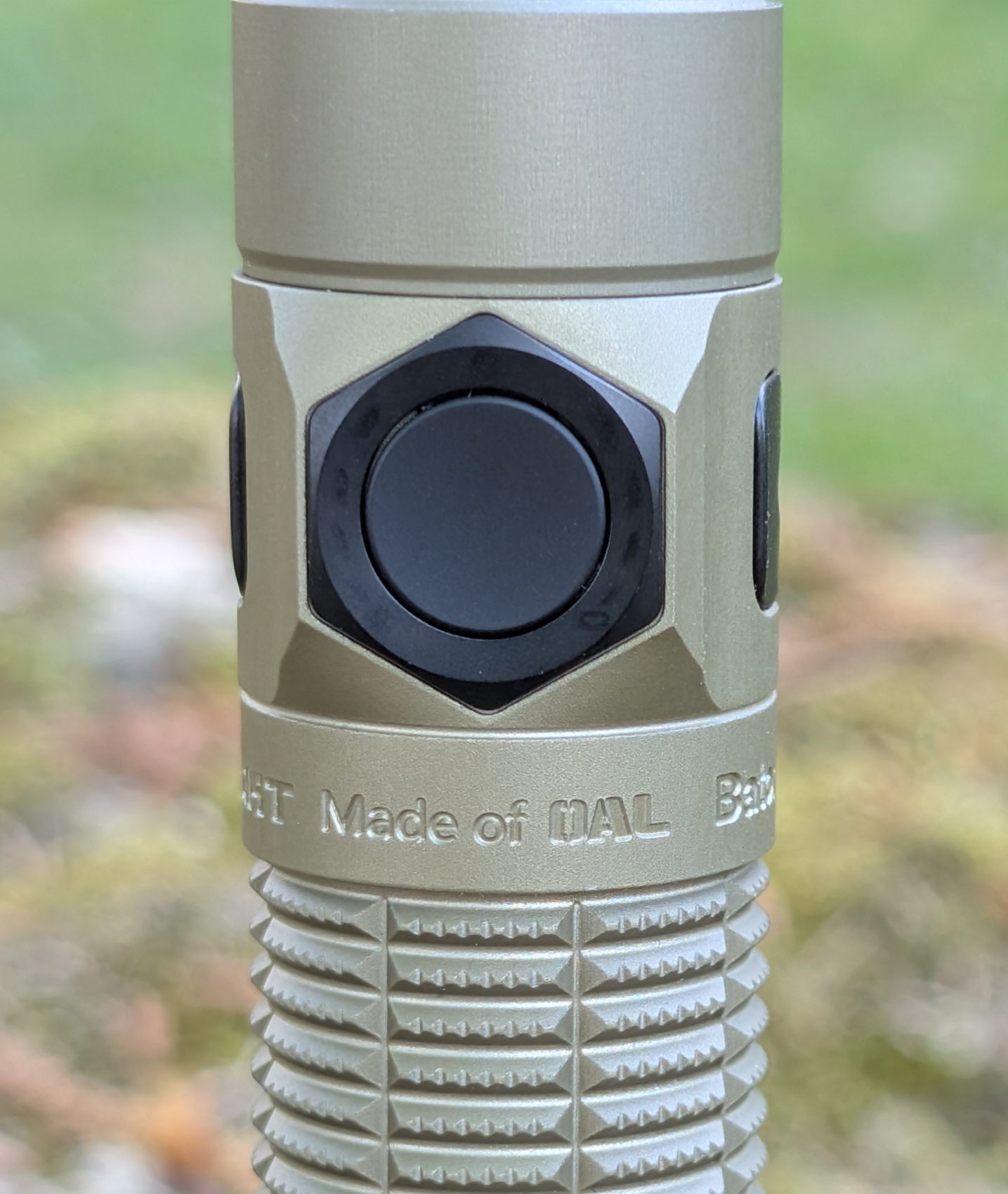 Gros plan side button Olight Baton Ultra - design hexagonal et inscription Made of OAL gravée dans le métal