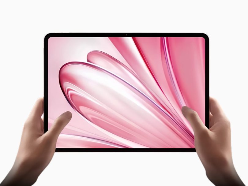 Main tenant une tablette compacte Oppo Pad Mini affichant un fond d'écran abstrait rose, illustrant son format réduit et son écran OLED aux bordures fines.
