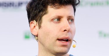 Portrait serré de Sam Altman, PDG d'OpenAI, s'exprimant avec un micro-casque lors d'une conférence technique.