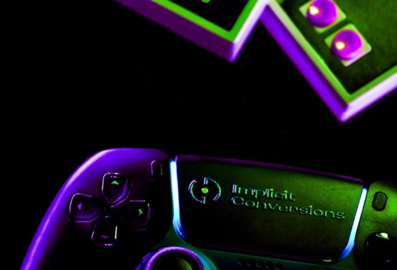 Gros plan sur une manette PlayStation avec le logo de Implicit Conversions illuminé en néon vert et violet, symbolisant l'émulation de jeux classiques.