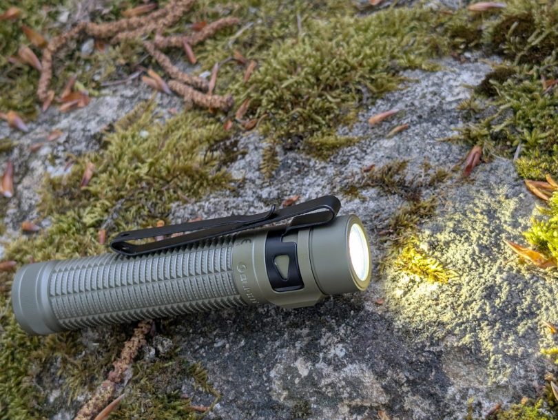 Test Olight Baton Ultra Desert Tan 2026 - lampe allumée en conditions réelles, faisceau EIP 1 sur rocher moussu