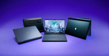 Quatre ordinateurs portables gaming Alienware disposés sur un fond violet épuré, mettant en valeur leurs lignes futuristes, le logo de la tête d'alien illuminé et un écran central affichant une illustration fantastique.