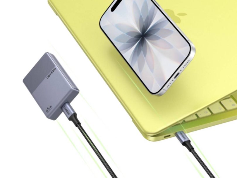 Chargeur ultra-compact Ugreen Nexode Air 45W gris au format "biscuit", connecté par un câble USB-C tressé à un ordinateur portable jaune sur lequel repose un smartphone.