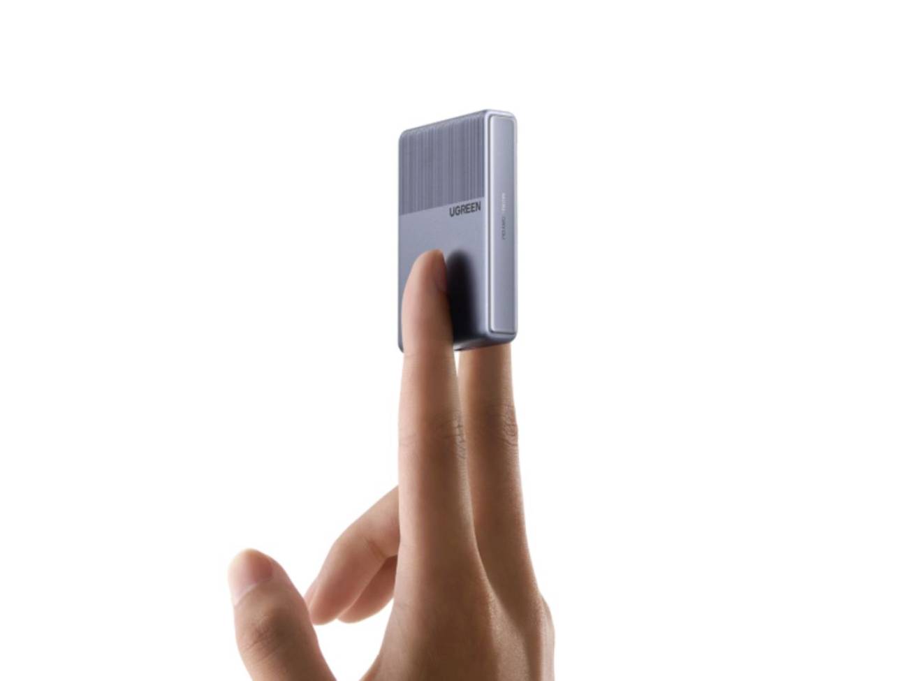 Une main tient le chargeur gris Ugreen Nexode Air 45W entre l'index et le majeur, mettant en évidence son épaisseur ultra-fine et son profil compact.