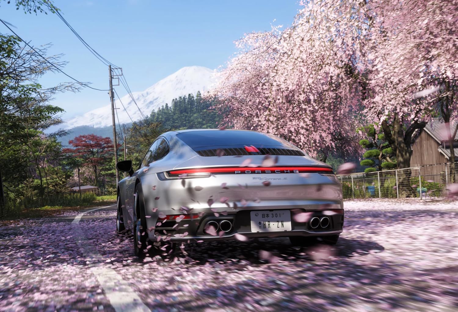 Arrière d'une Porsche 911 Carrera grise roulant sous des cerisiers en fleurs (sakura) avec le Mont Fuji en arrière-plan dans Forza Horizon 6.