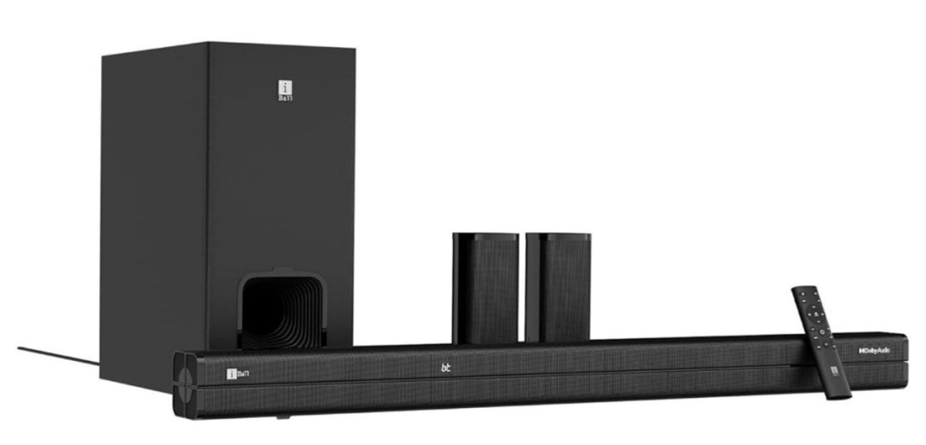 Système iBall Cinebar 560 complet en vue de trois-quarts : caisson de basses sans-fil vertical, deux satellites arrière cylindriques et barre de son frontale avec logos Dolby Audio et Bluetooth visibles, télécommande posée sur la barre.