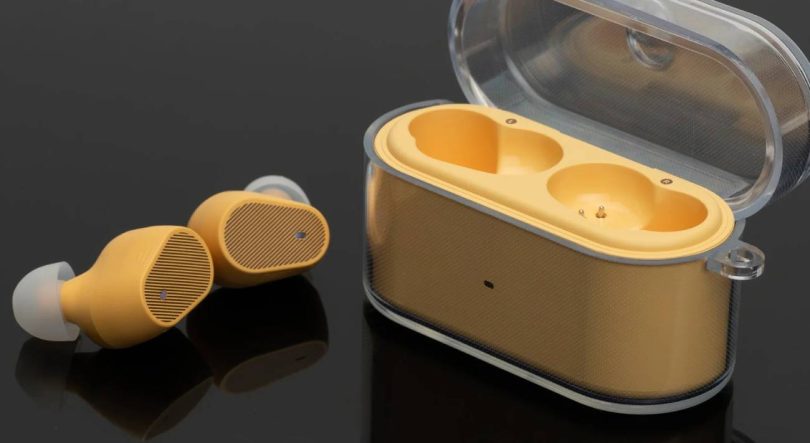 Écouteurs TWS Moondrop Pudding coloris jaune avec embouts silicone translucides, posés à côté de leur boîtier de recharge ouvert à couvercle transparent, photographiés sur fond noir.