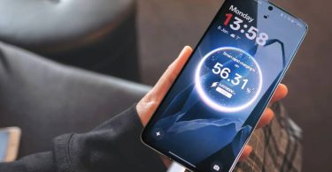 Smartphone OnePlus en main affichant la recharge rapide SuperVOOC 100W, branché via son port USB-C.