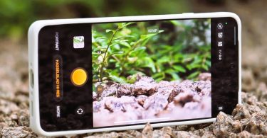 Vue rapprochée de l'écran de l'Oppo Find X9 Ultra en train de cadrer une photo macro de graviers et de plantes. L'interface affiche le mode Hasselblad Hi-Res et un curseur de zoom, illustrant les capacités du capteur 200 MPX.