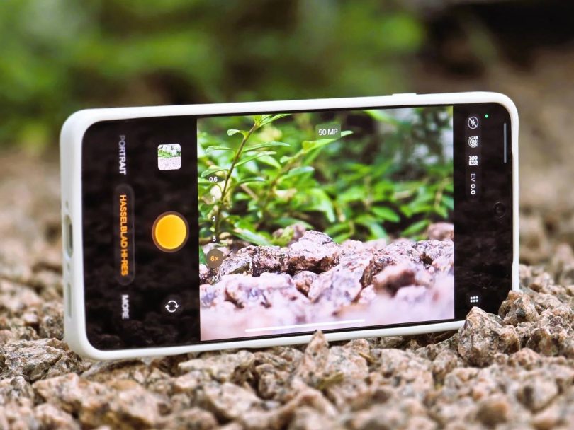 Vue rapprochée de l'écran de l'Oppo Find X9 Ultra en train de cadrer une photo macro de graviers et de plantes. L'interface affiche le mode Hasselblad Hi-Res et un curseur de zoom, illustrant les capacités du capteur 200 MPX.