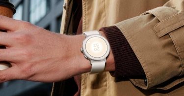 Realme Watch S5 coloris Sand White portée au poignet, boîtier rond au profil plat, trois boutons latéraux et écran AMOLED circulaire affichant l'heure en extérieur.