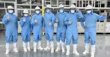 Visite de l'usine TCL CSOT T6/T7 à Shenzhen, équipe d'ingénieurs en combinaisons stériles bleues et casques blancs dans la salle blanche de fabrication des dalles LCD MiniLED en verre G11.