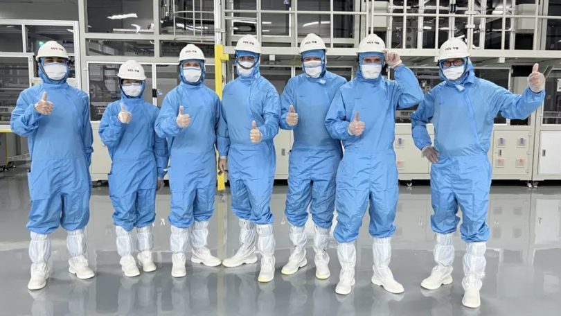 Visite de l'usine TCL CSOT T6/T7 à Shenzhen, équipe d'ingénieurs en combinaisons stériles bleues et casques blancs dans la salle blanche de fabrication des dalles LCD MiniLED en verre G11.