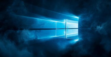 Logo lumineux de Windows 11 diffusant une lumière bleue stylisée à travers une brume sombre, illustrant la mise à jour logicielle KB5083631 et ses nouvelles fonctionnalités de performance.