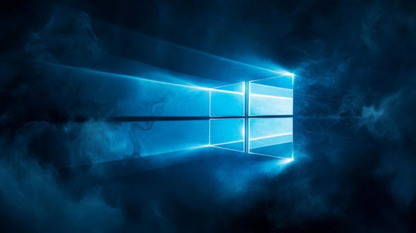 Logo lumineux de Windows 11 diffusant une lumière bleue stylisée à travers une brume sombre, illustrant la mise à jour logicielle KB5083631 et ses nouvelles fonctionnalités de performance.