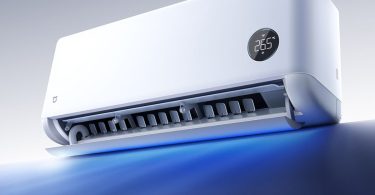 Visuel promotionnel du climatiseur connecté Xiaomi Mijia Air Conditioner Powerful Airflow Over 1.5HP. L'unité intérieure blanche est vue en perspective, le volet inférieur est ouvert, laissant jaillir un faisceau de lumière bleue symbolisant le débit d'air puissant de 900 m³/h. L'écran circulaire intégré affiche la température de 26,5°C et l'icône Wi-Fi, confirmant ses fonctionnalités connectées.