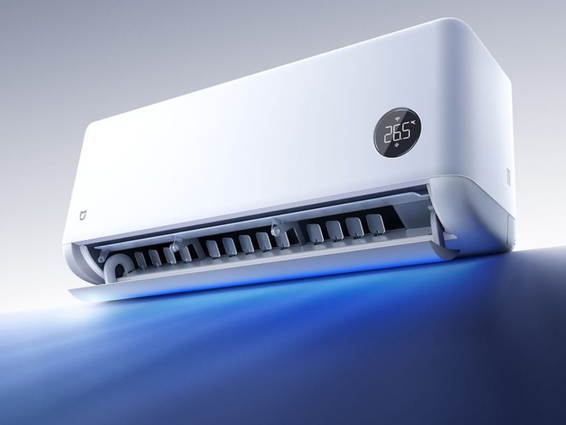 Visuel promotionnel du climatiseur connecté Xiaomi Mijia Air Conditioner Powerful Airflow Over 1.5HP. L'unité intérieure blanche est vue en perspective, le volet inférieur est ouvert, laissant jaillir un faisceau de lumière bleue symbolisant le débit d'air puissant de 900 m³/h. L'écran circulaire intégré affiche la température de 26,5°C et l'icône Wi-Fi, confirmant ses fonctionnalités connectées.