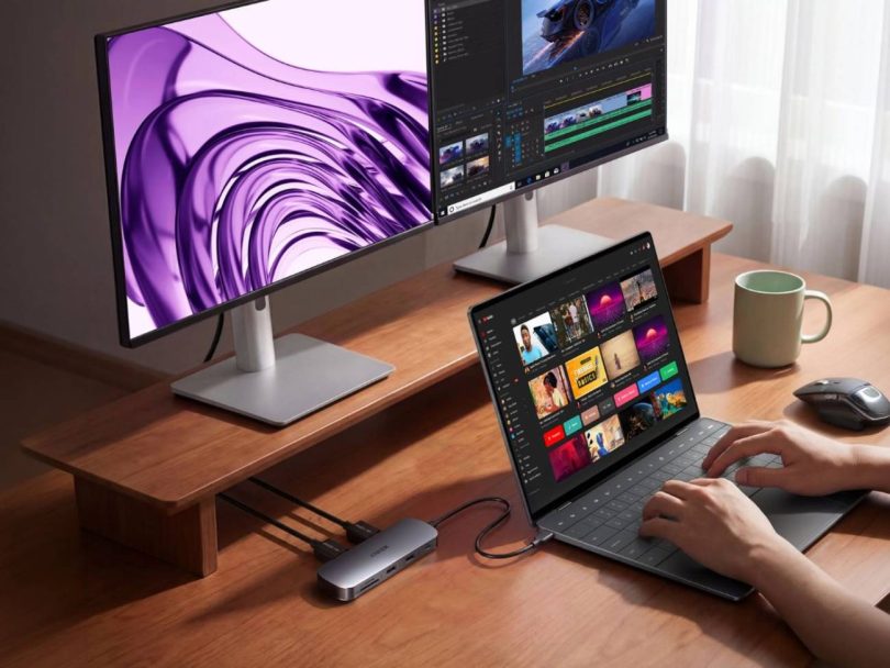 Hub USB-C 8-en-1 Nano d'Anker branché à un ordinateur portable sur un bureau en bois, gérant un double affichage fluide sur deux moniteurs externes en 4K.