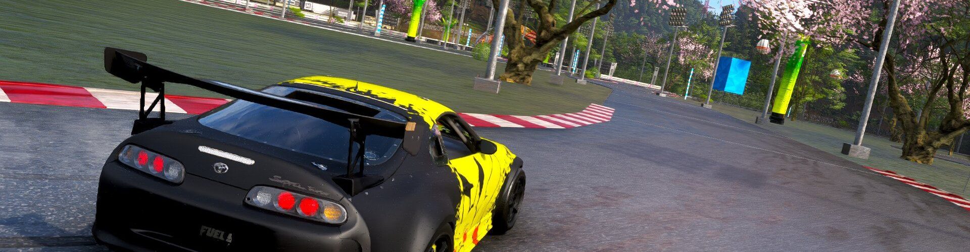 Capture d'écran du jeu Forza Horizon 6 montrant une Toyota Supra noire et jaune négociant un virage sur un circuit asphalté, entouré de cerisiers en fleurs (sakura) typiques des paysages japonais.