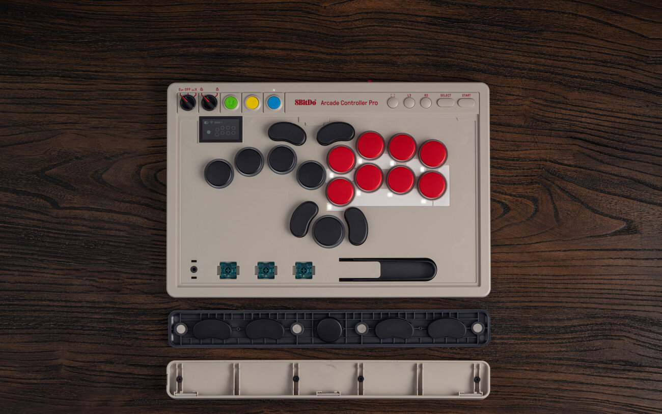 8BitDo Arcade Controller Pro vu de dessus avec son repose-poignets magnétique retiré, révélant trois switchs Core Green de rechange et l'extracteur rangés dans le compartiment