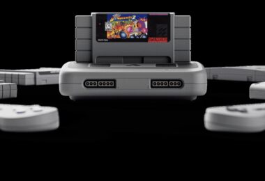 Console Analogue Super Nt+ grise avec une cartouche Super Nintendo insérée, entourée de manettes, nouvelle console rétro FPGA compatible cartouches originales en 1080p