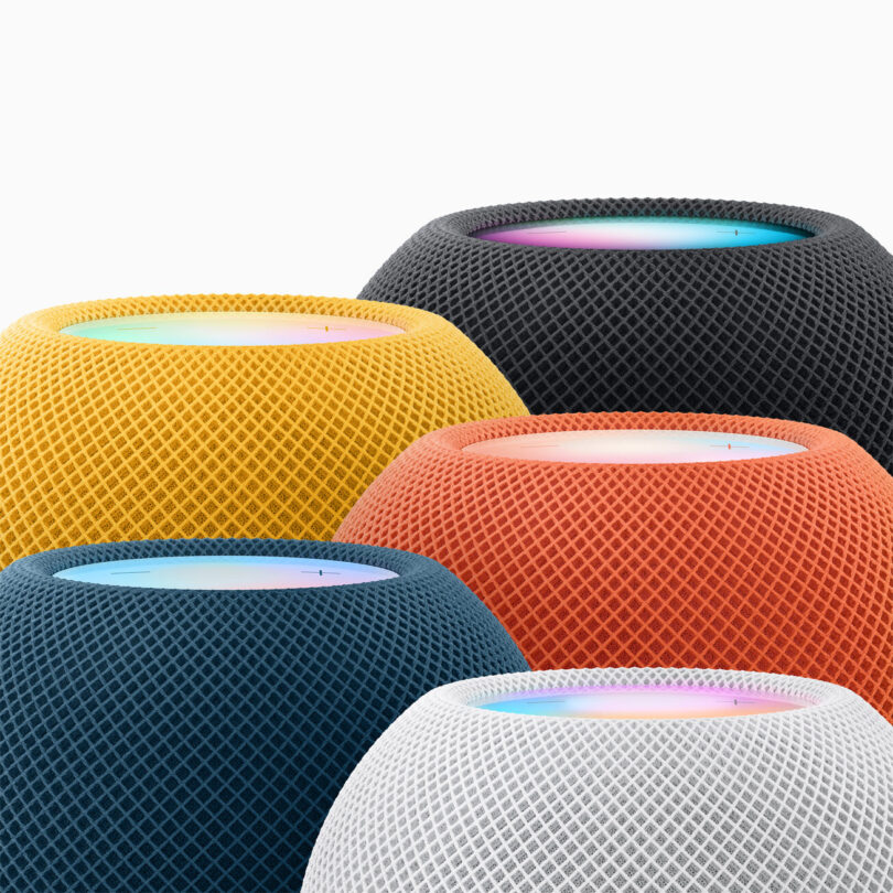 Cinq enceintes HomePod mini actuelles regroupées, en jaune, minuit, orange, bleu et blanc, avec leur dessus tactile lumineux