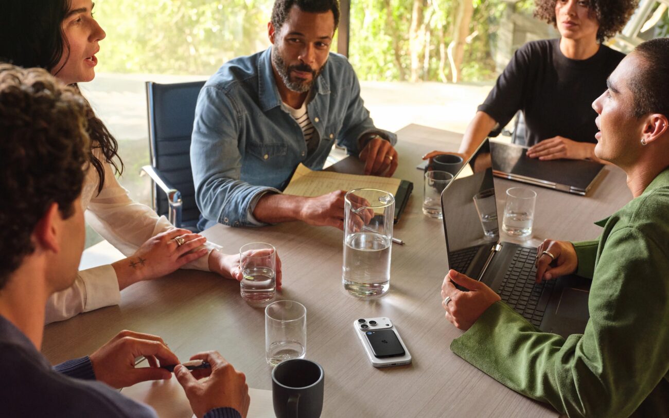 Réunion de travail autour d'une table avec un smartphone posé dos visible, équipé de la carte aimantée Bee Eclipse qui enregistre la discussion