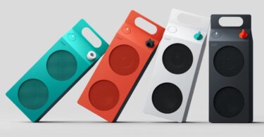 Les quatre coloris de l'enceinte Bluetooth CMF Speaker M de Nothing (turquoise, orange, blanc et gris foncé) alignés, avec leur forme de brique de lait et leur poignée intégrée
