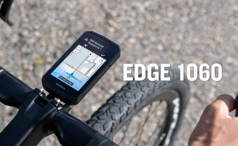 Le compteur vélo GPS Garmin Edge 1060 fixé sur le cintre d'un vélo de route, écran tactile 3,5 pouces affichant une alerte nid-de-poule
