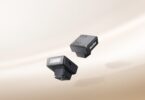 Deux mini flashs Godox iM10 noirs posés sur un fond beige, avec leur tube éclair frontal et leur pied de griffe porte-accessoire