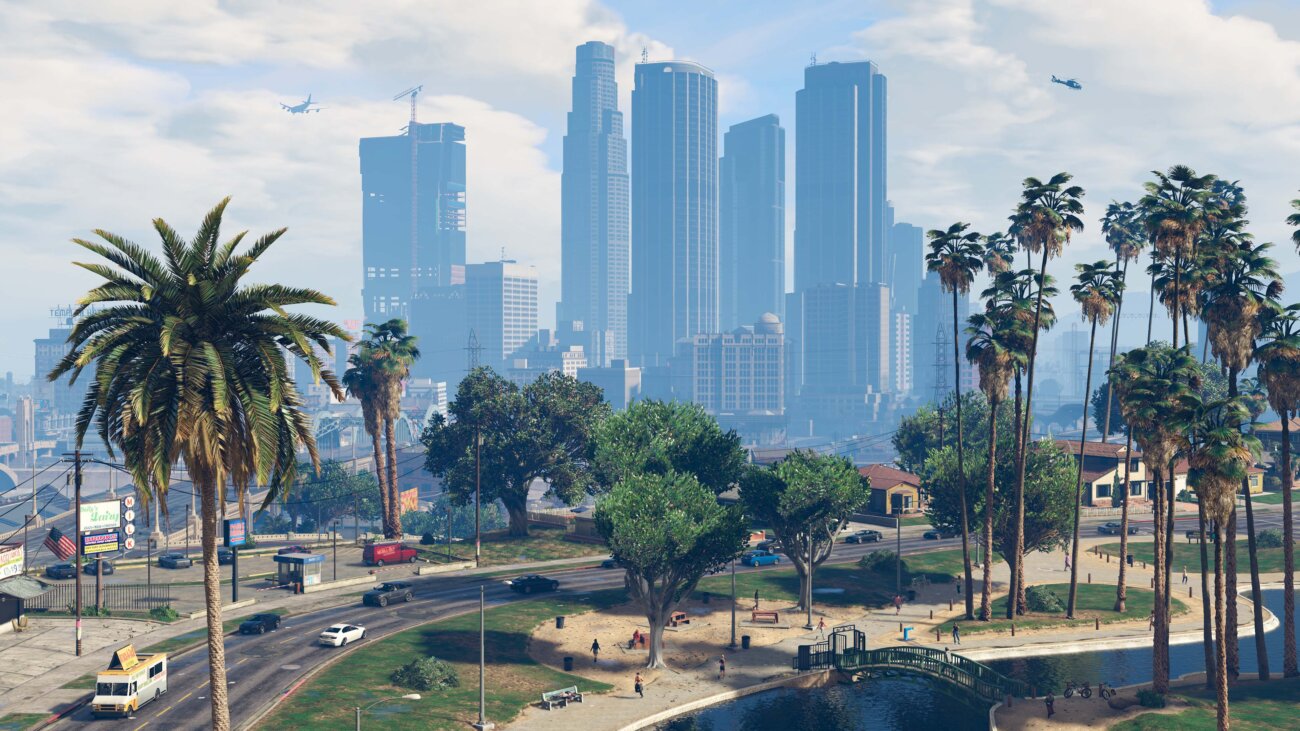 Le centre-ville de Los Santos en plein jour dans GTA V, avec ses tours de verre, ses palmiers et un parc en contrebas