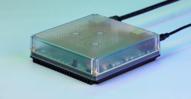 Box domotique Home Assistant Green avec son boîtier transparent et son dissipateur noir, branchée sur fond bleu vert, alternative prête à l'emploi au mini PC installé par clé USB