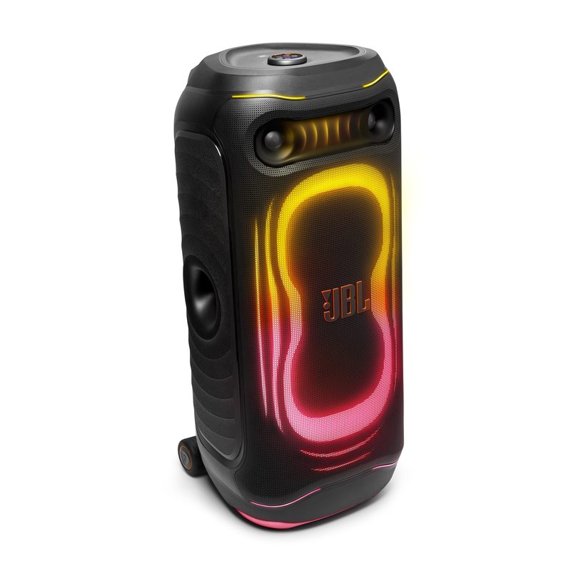 Enceinte de soirée JBL PartyBox Ultimate 2 vue de trois quarts sur fond blanc, façade éclairée en dégradé jaune, orange et rose, tweeters en haut, woofer latéral et roulettes de transport