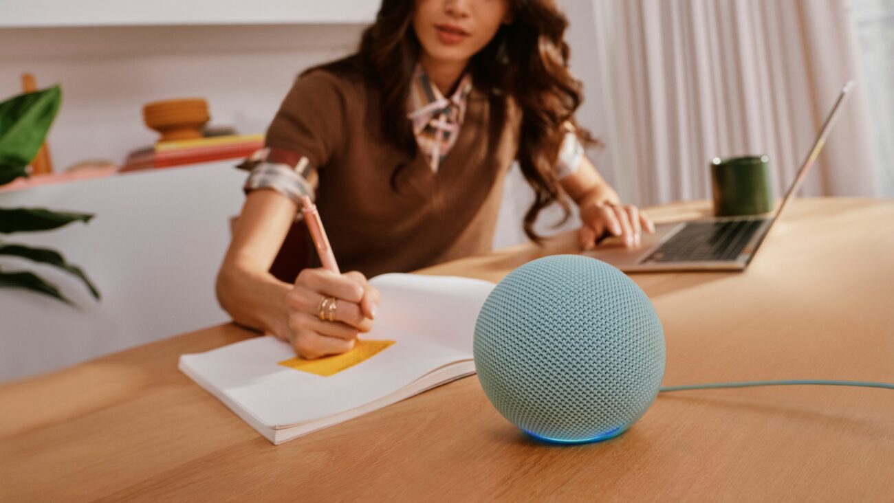 Nouvel Amazon Echo Dot bleu-vert posé sur un bureau en bois, enceinte connectée avec hub domotique Zigbee, Matter et Thread et répéteur eero intégrés