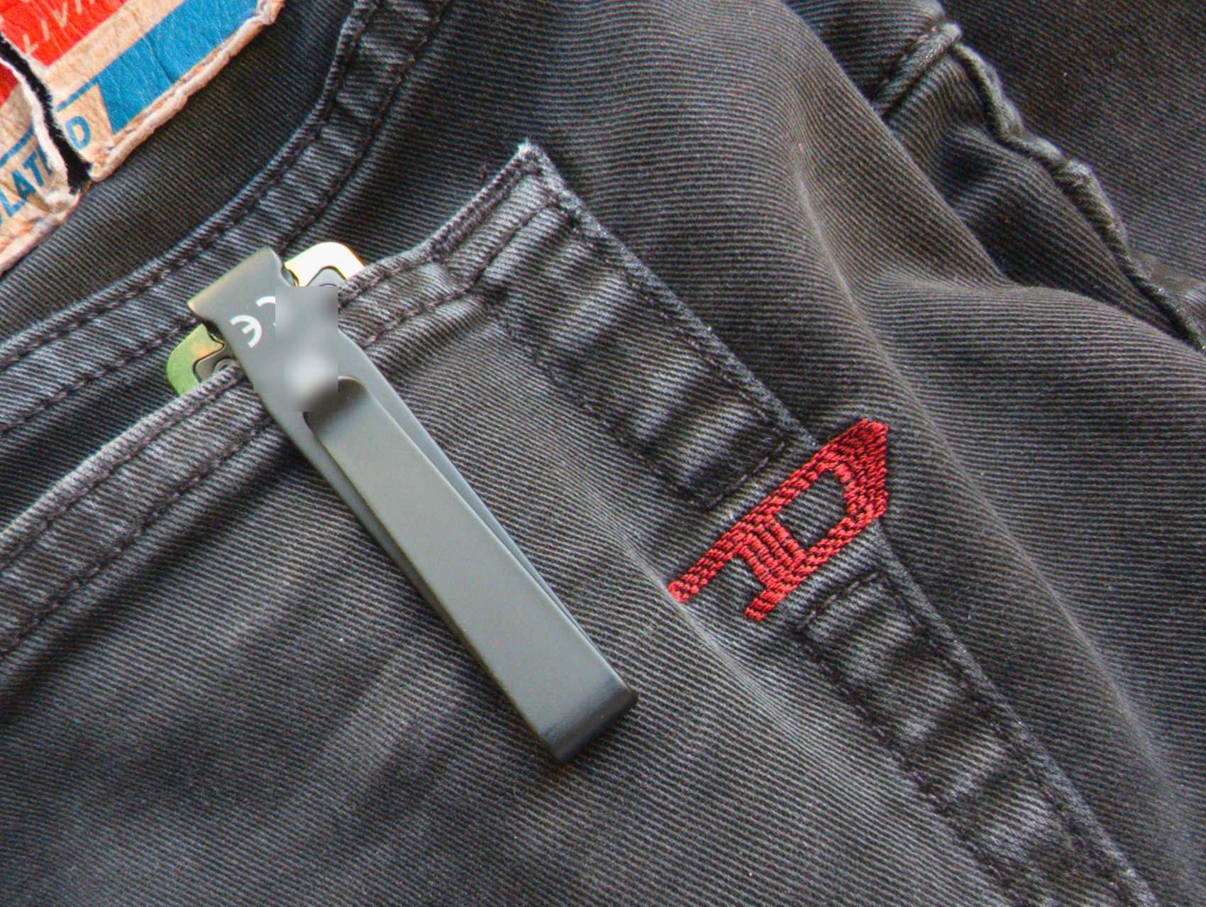 Olight ArkPro clipsée dans la poche arrière d'un jean, clip noir visible