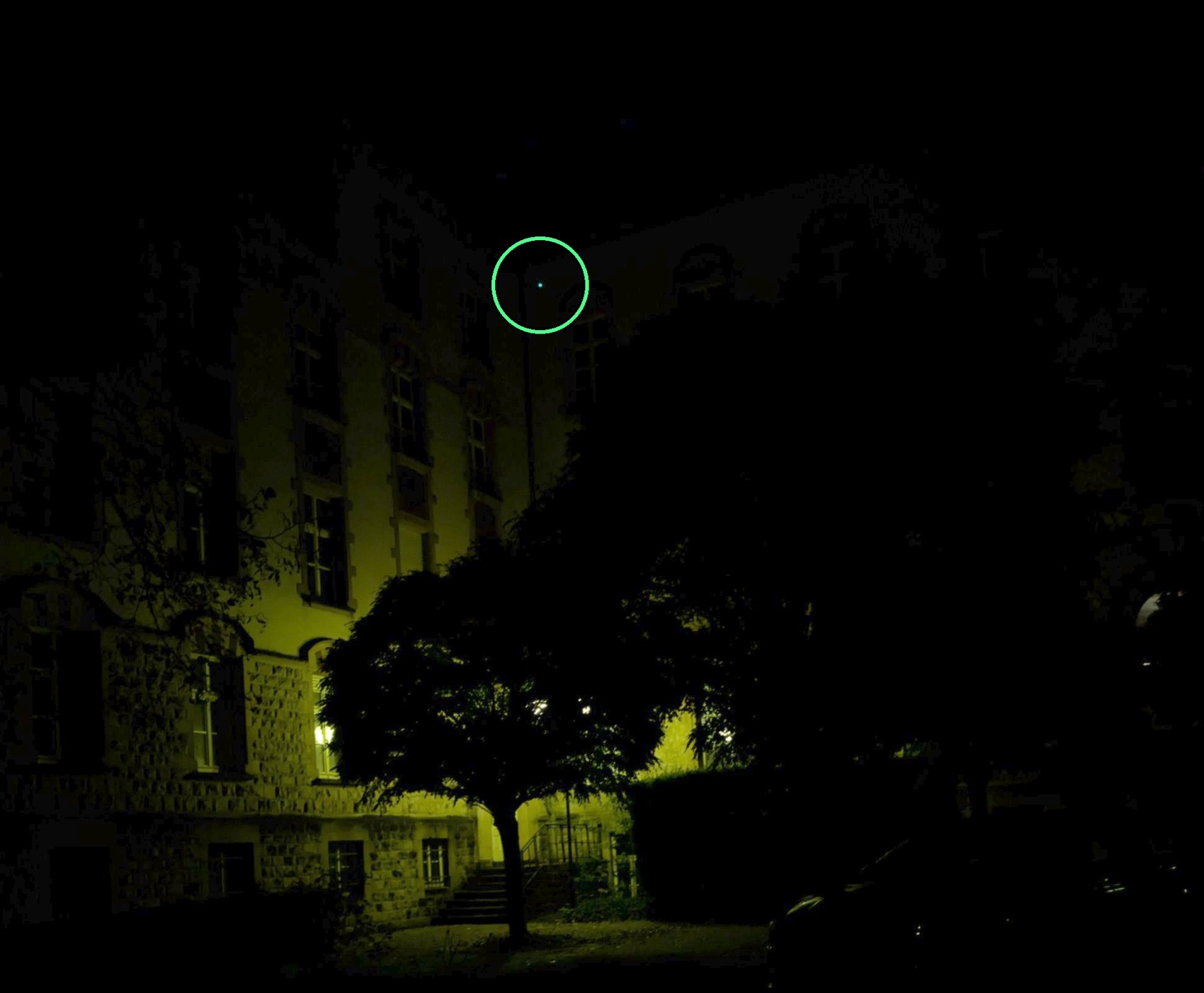 Point du laser vert de l'Olight ArkPro, entouré, en haut d'un immeuble à au moins 100 mètres, de nuit