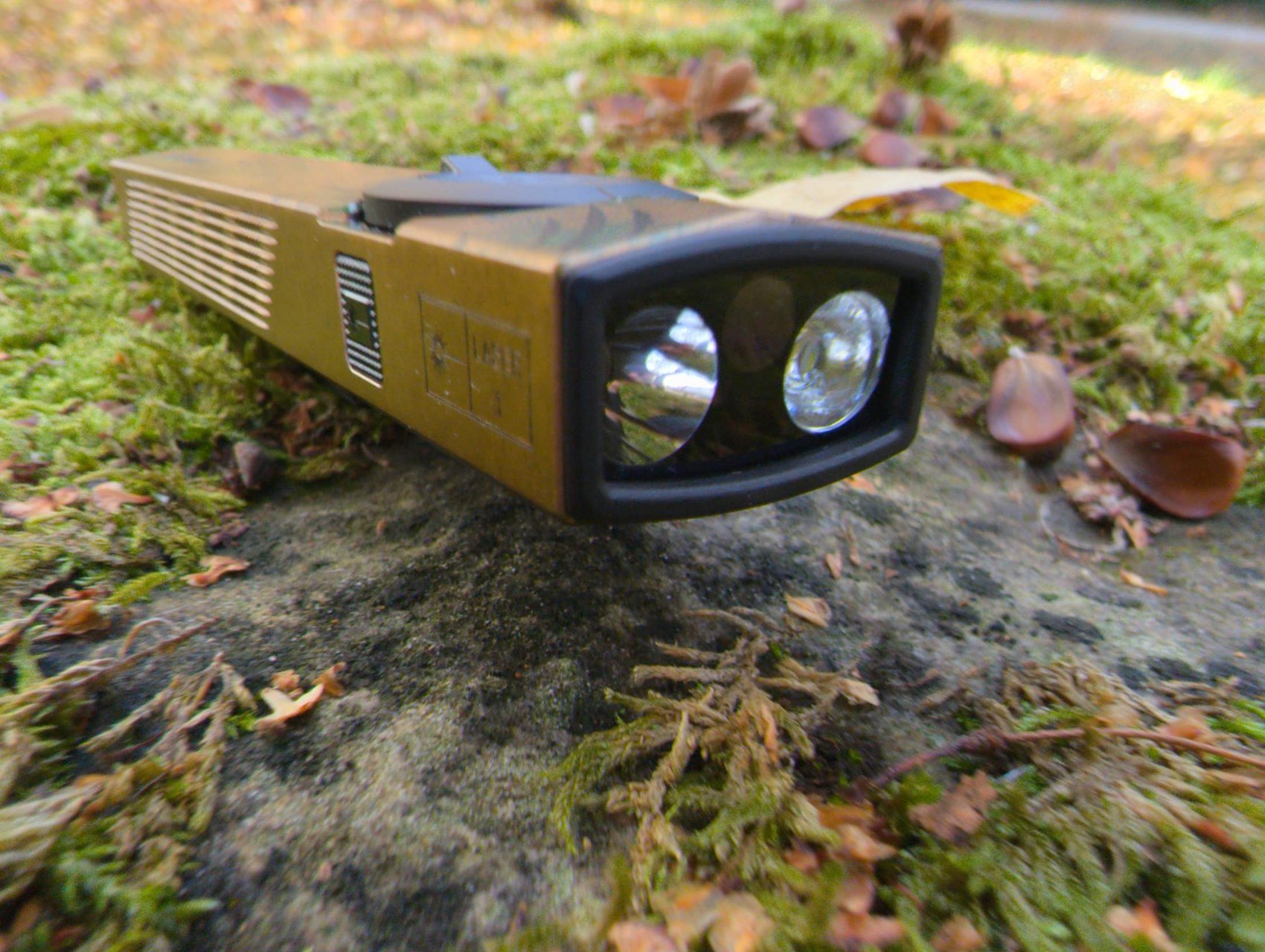Tête de l'Olight ArkPro vue de trois quarts avec les optiques Pure Flood et Spot, posée sur un rocher