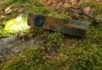 Olight ArkPro Ultra édition Relique des terres désolées allumée en Pure Flood, posée sur un rocher moussu en automne