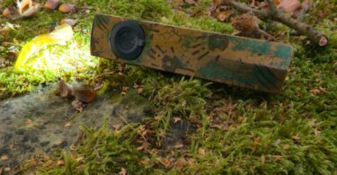 Olight ArkPro Ultra édition Relique des terres désolées allumée en Pure Flood, posée sur un rocher moussu en automne